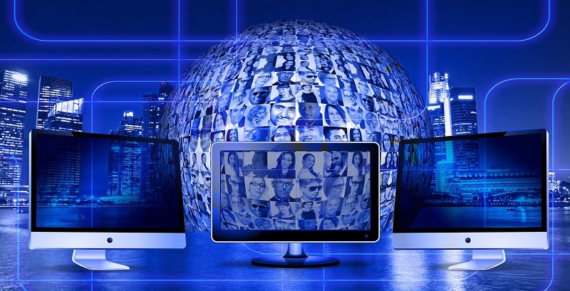 Computer screen with people on it, in front of a globe like structure with faces on